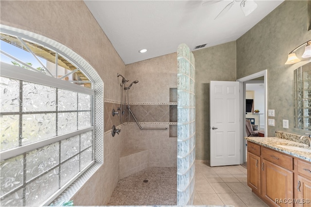 bathroom featuring tile patterned flooring, a tile shower, vanity, and ceiling fan