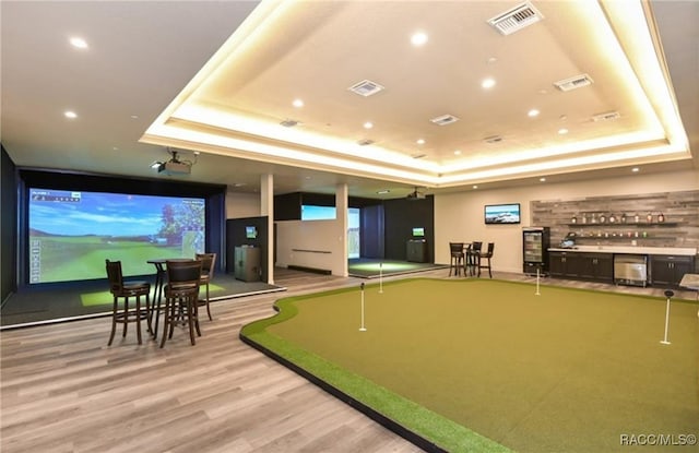 game room with a tray ceiling and light wood-type flooring