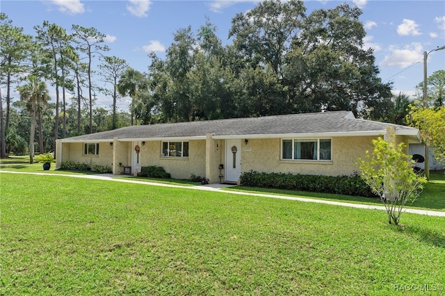 ranch-style home featuring a front lawn and stucco siding