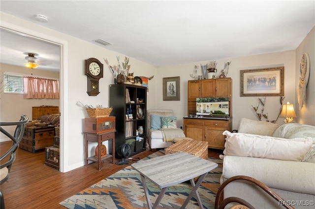 living room featuring dark wood-style flooring, visible vents, and baseboards