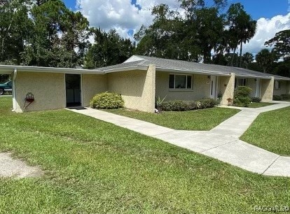 ranch-style house with a front lawn and stucco siding