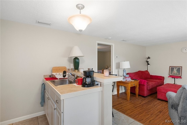 interior space with light tile patterned floors, open floor plan, a peninsula, light countertops, and a sink