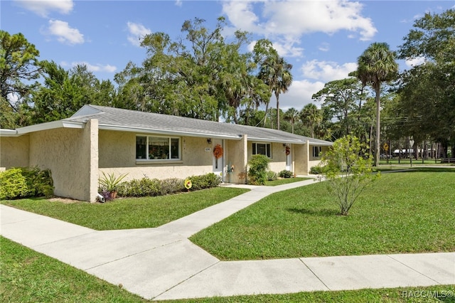 ranch-style home with a front yard and stucco siding