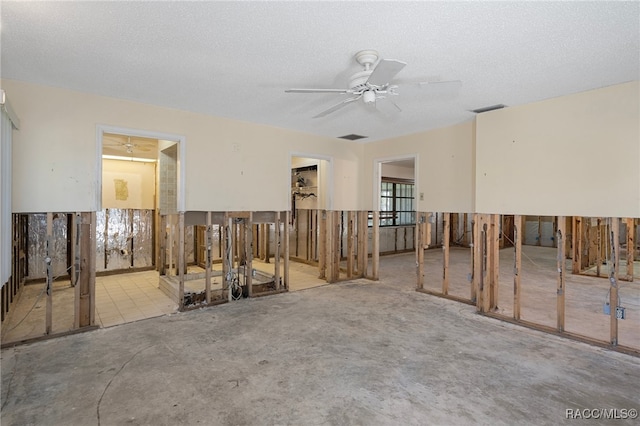 empty room with ceiling fan and a textured ceiling