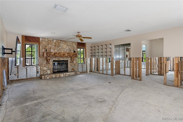 unfurnished living room with a fireplace, a textured ceiling, and ceiling fan