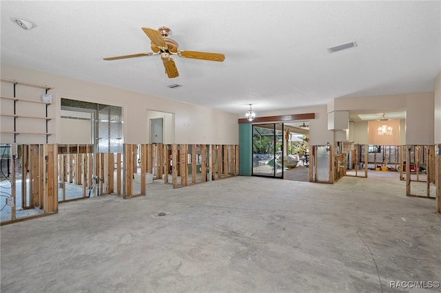 interior space featuring concrete flooring, a textured ceiling, and ceiling fan with notable chandelier