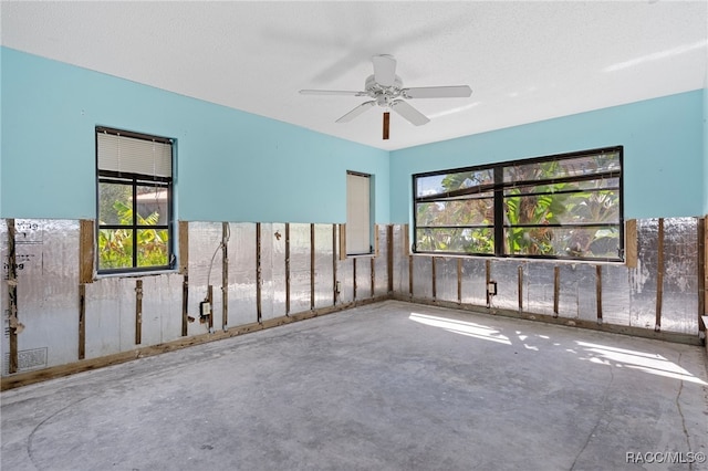 unfurnished room featuring ceiling fan, concrete flooring, and a textured ceiling