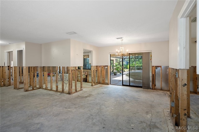 unfurnished room with a notable chandelier, a textured ceiling, and concrete floors