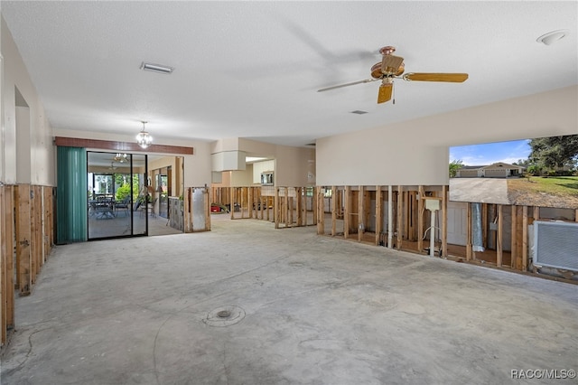 miscellaneous room featuring a textured ceiling, plenty of natural light, concrete flooring, and ceiling fan with notable chandelier