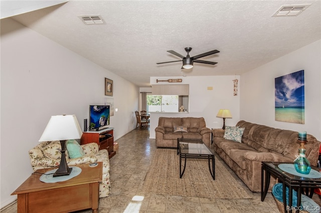 living room featuring ceiling fan and a textured ceiling