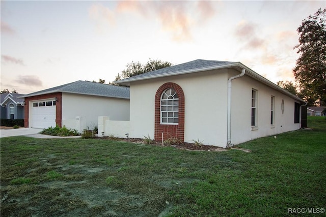 property exterior at dusk with a garage and a yard