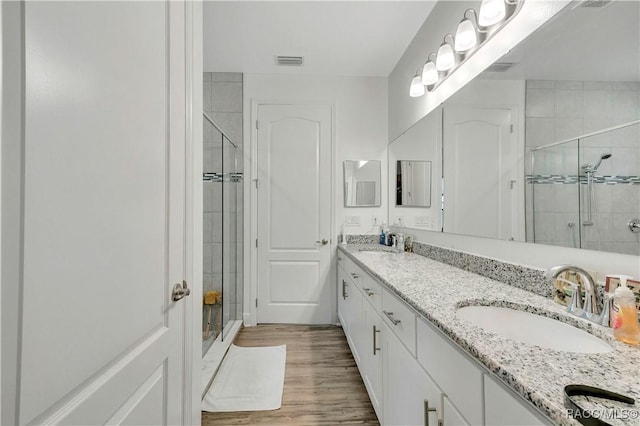 bathroom featuring a shower with door, vanity, and wood-type flooring