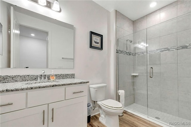 bathroom featuring hardwood / wood-style flooring, vanity, toilet, and a shower with shower door