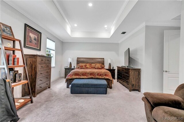 bedroom featuring ornamental molding, light carpet, and a tray ceiling