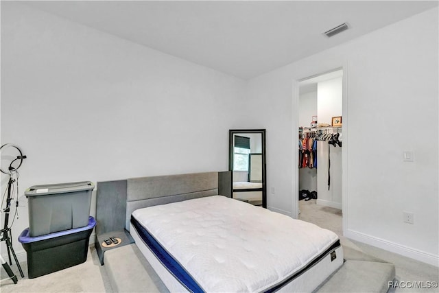 bedroom featuring a spacious closet, a closet, and light colored carpet