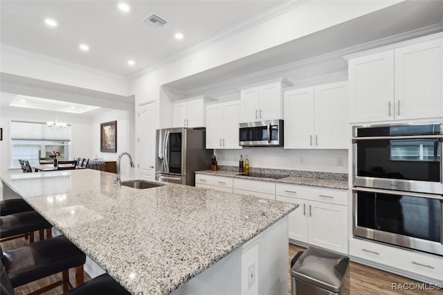 kitchen with a kitchen breakfast bar, stainless steel appliances, white cabinetry, and a large island