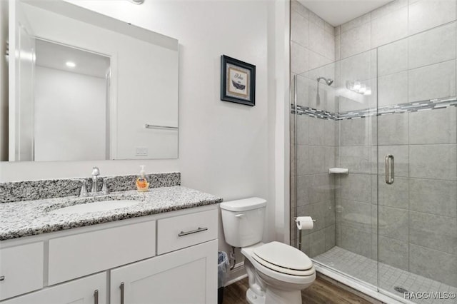 bathroom with wood-type flooring, vanity, toilet, and an enclosed shower