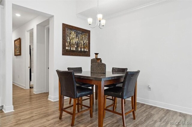 dining room with crown molding, a chandelier, and light hardwood / wood-style floors