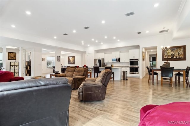 living room featuring a chandelier, light hardwood / wood-style flooring, and crown molding