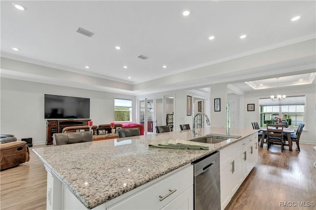 kitchen featuring a tray ceiling, a spacious island, sink, dishwasher, and white cabinetry