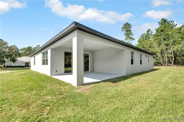 back of property featuring a lawn and a patio