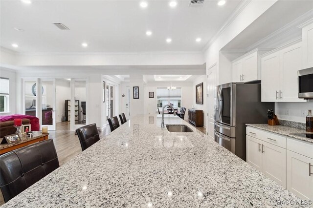 kitchen with light stone countertops, white cabinetry, a breakfast bar area, and sink