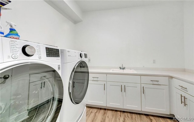 laundry area featuring sink, light hardwood / wood-style flooring, cabinets, and independent washer and dryer