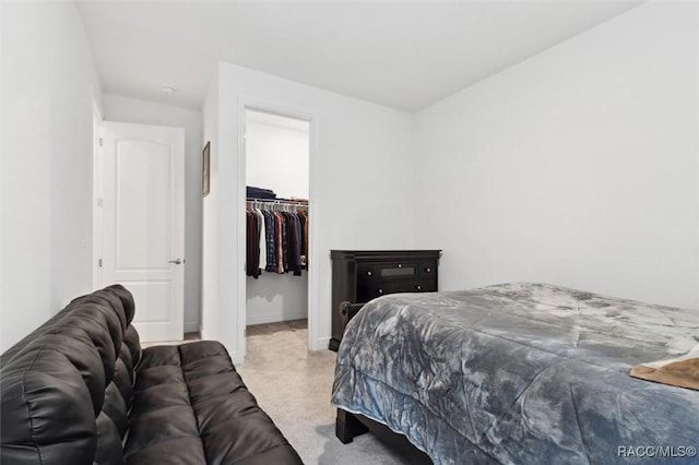 carpeted bedroom featuring a walk in closet and a closet