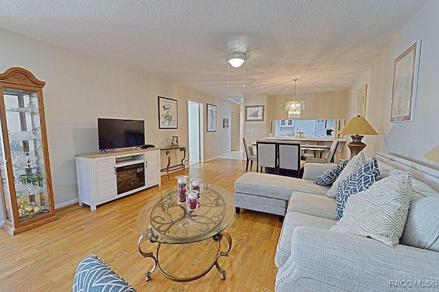 living room featuring a textured ceiling, light wood-type flooring, and a notable chandelier