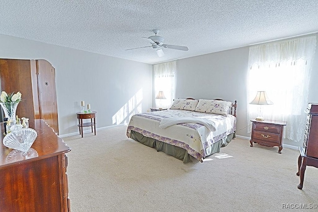 bedroom featuring light carpet, a textured ceiling, and ceiling fan