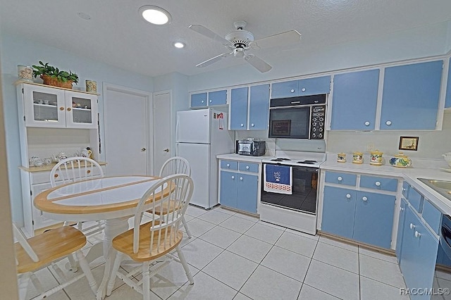 kitchen featuring a textured ceiling, white appliances, blue cabinets, and light tile patterned floors