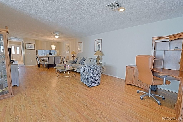 home office with ceiling fan, light hardwood / wood-style flooring, and a textured ceiling