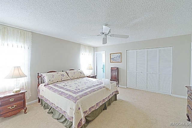 bedroom with ceiling fan, light colored carpet, and a textured ceiling