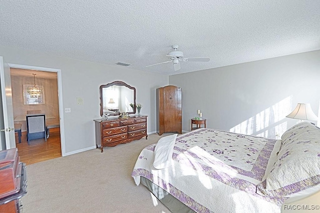 carpeted bedroom featuring ceiling fan and a textured ceiling