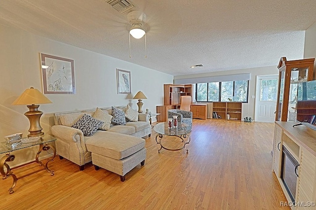 living room with a textured ceiling and light wood-type flooring