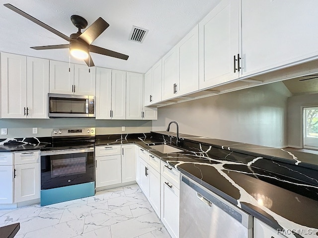 kitchen featuring appliances with stainless steel finishes, white cabinetry, ceiling fan, and sink