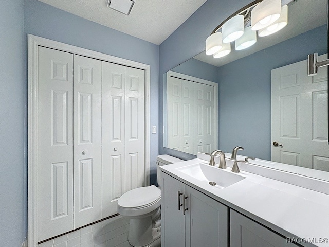 bathroom featuring tile patterned flooring, vanity, a textured ceiling, and toilet