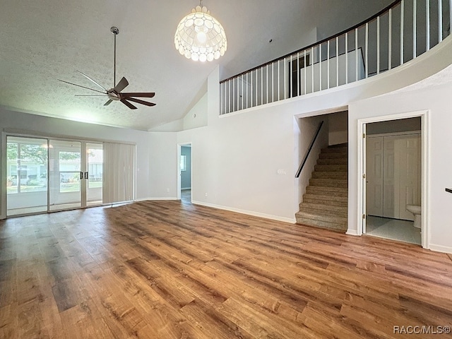 unfurnished living room with a textured ceiling, hardwood / wood-style flooring, high vaulted ceiling, and ceiling fan