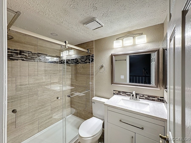 bathroom with an enclosed shower, vanity, toilet, and a textured ceiling