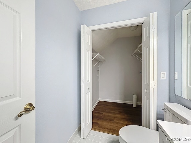 bathroom featuring a textured ceiling, vanity, hardwood / wood-style flooring, toilet, and lofted ceiling