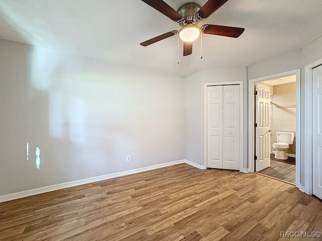 unfurnished bedroom with hardwood / wood-style flooring, ceiling fan, and ensuite bath