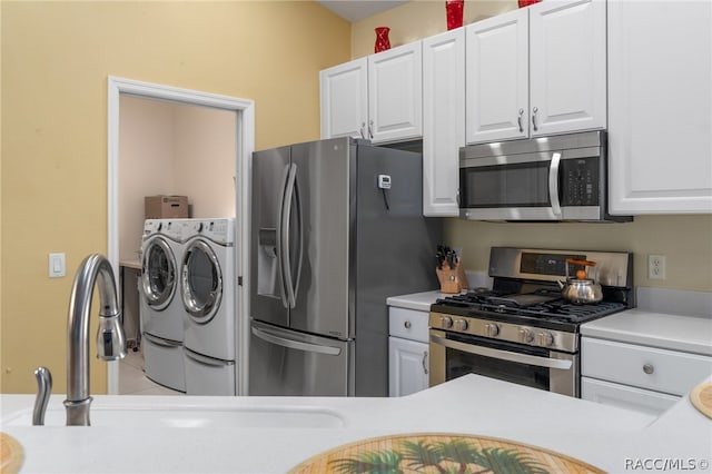 kitchen with appliances with stainless steel finishes, independent washer and dryer, and white cabinetry