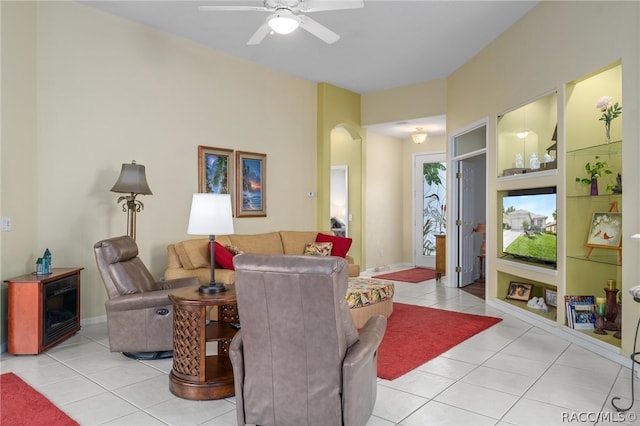 tiled living room featuring built in shelves and ceiling fan