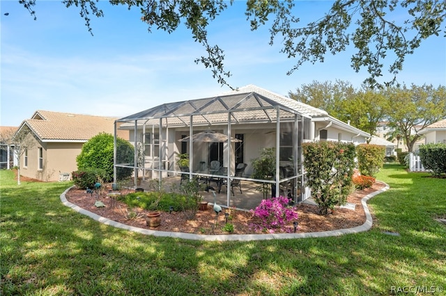 rear view of house featuring a yard and glass enclosure