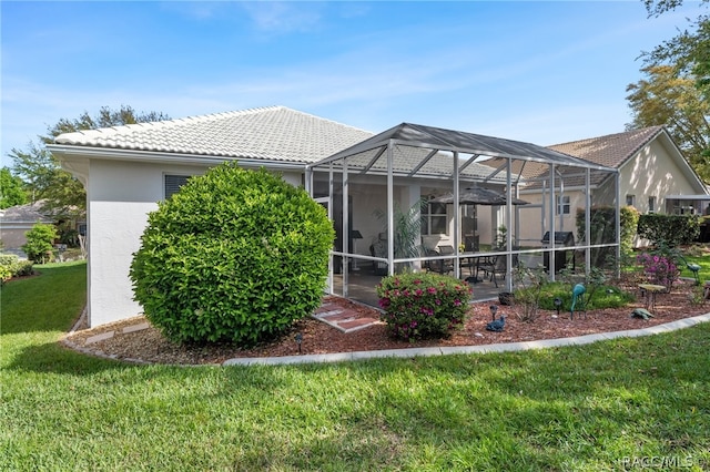 rear view of property featuring a lanai and a lawn