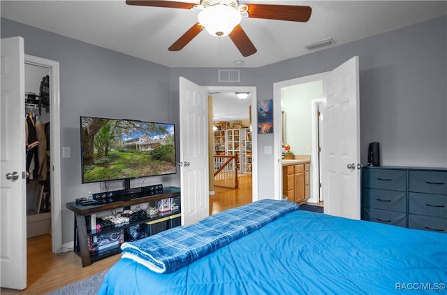 bedroom with hardwood / wood-style flooring, ceiling fan, and ensuite bath