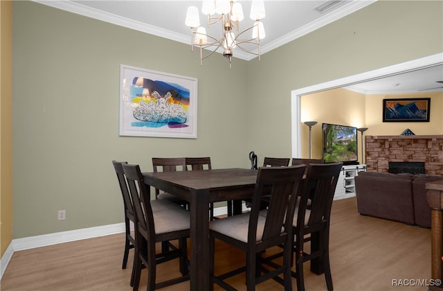 dining area featuring hardwood / wood-style flooring, a stone fireplace, and ornamental molding