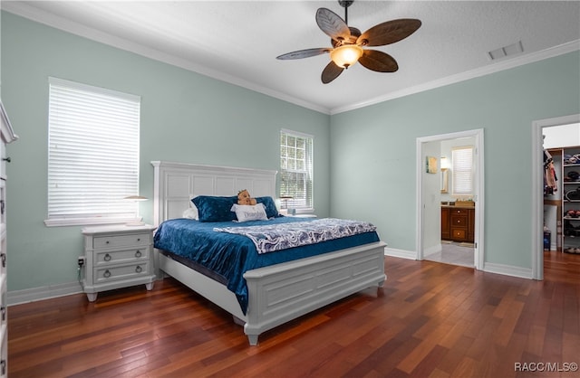 bedroom featuring connected bathroom, ceiling fan, dark wood-type flooring, a walk in closet, and ornamental molding