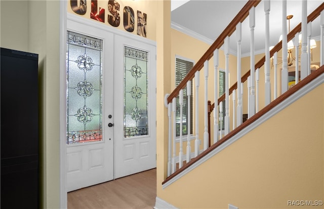 entrance foyer with ornamental molding, french doors, and light hardwood / wood-style flooring