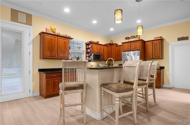 kitchen featuring decorative light fixtures, stainless steel appliances, crown molding, and a kitchen breakfast bar